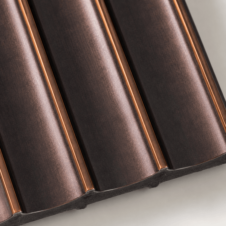 Close-up of the Antique Bronze Fluted PS Wall Panel featuring a dark metallic finish with evenly spaced, curved fluted ridges and subtle copper highlights, reminiscent of contemporary architectural design, photographed on a light background.