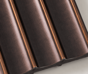 Close-up of the Antique Bronze Fluted PS Wall Panel featuring a dark metallic finish with evenly spaced, curved fluted ridges and subtle copper highlights, reminiscent of contemporary architectural design, photographed on a light background.