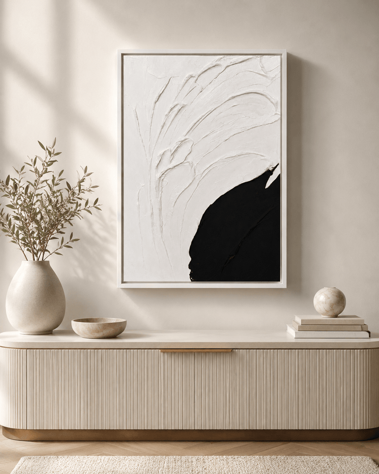 Minimalist sideboard with ceramic vases, green plant, and black and white abstract wall art above.