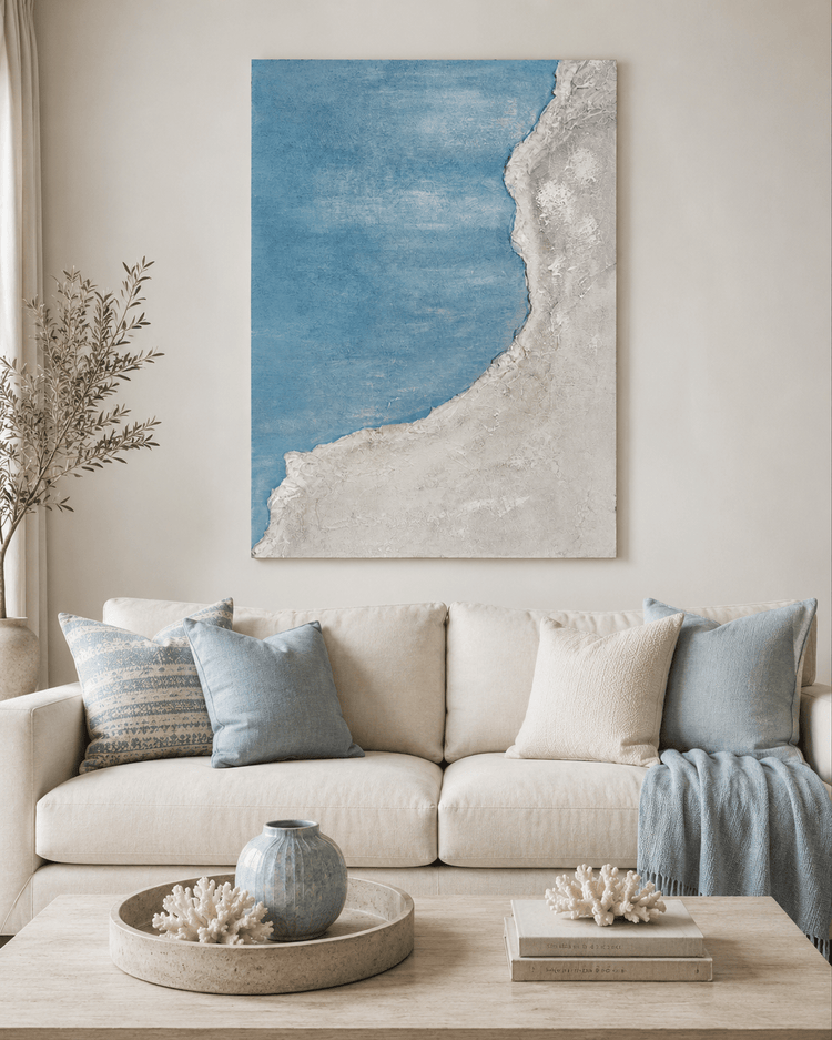 Beige sofa with blue pillows, abstract coastal wall art, and wooden coffee table decor in a living room setting.