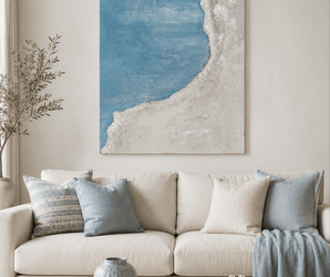 Beige sofa with blue pillows, abstract coastal wall art, and wooden coffee table decor in a living room setting.