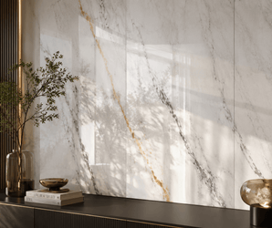WALLSMARK Calacatta Aurelia Marble wall with gray and gold veins, black console, vase with branch, dish, and lamp.