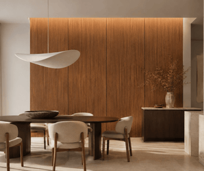 Minimalist dining room with a dark wood table, six cream chairs, sculptural white pendant light, Derby Saddle Wood Look Panels on the wall, sideboard, and vase with dried branches in natural light.