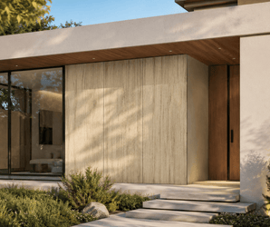 Natural stone look wall tiles on a modern house exterior with large windows, wooden door, and green landscaping.