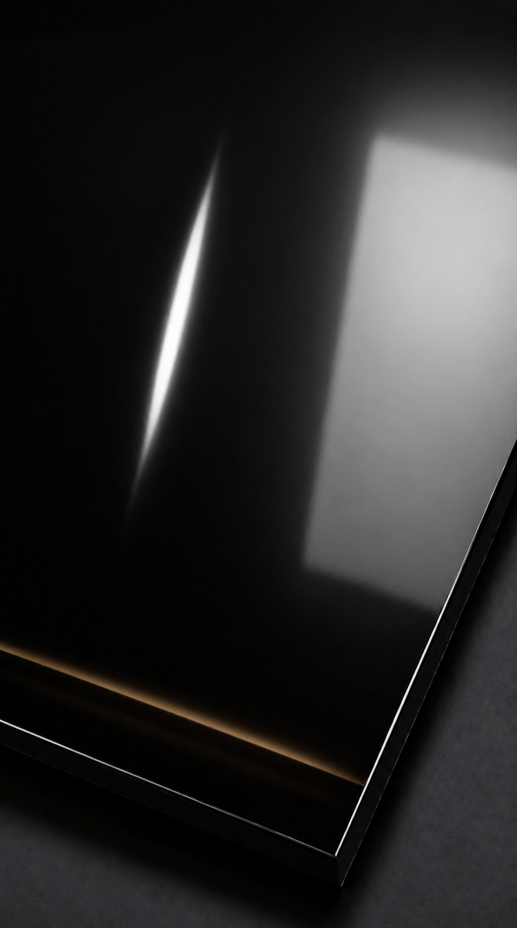 High-gloss black wall panel with reflective finish, showing light, window reflection, and a scratch near the center.