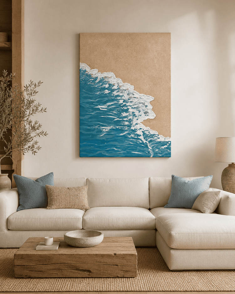 Wallsmark INC Ocean Shore Coastal Wall Art above beige sofa with blue pillows and wooden table in bright living room.