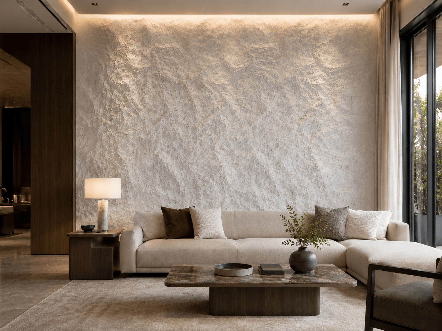 Modern living room featuring a textured accent wall clad in Rocky White PU Stone Panel, complemented by a sleek decorative wall panel, beige sectional sofa, marble coffee table, neutral decor, and a large window flooding the space with natural light. The minimalist design is enhanced by warm lighting and earthy tones throughout.