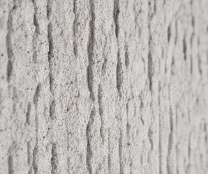 Textured concrete wall panel with vertical grooves, natural stone pattern, rough finish, and uneven surface details.